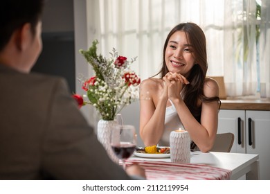 Asian Young Couple Having Dinner To Celebrate Valentine's Day Together. Attractive Romantic New Marriage Man And Woman Having Night Party Eat Foods On Table For Wedding Anniversary In Kitchen At Home.