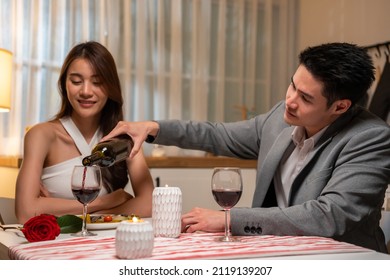 Asian Young Couple Having Dinner To Celebrate Valentine's Day Together. Attractive Romantic New Marriage Man And Woman Having Night Party Eat Foods On Table For Wedding Anniversary In Kitchen At Home.