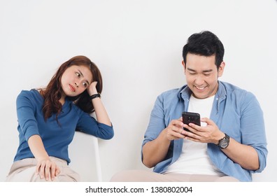 Asian Young Couple Lover Fighting For A Smart Phone In Living Room At Home.