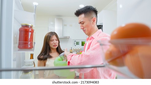 Asian Young Couple Open Refrigerator In Kitchen And There Has Bad Smell From Food Or Dishes Then They Pour It Into Trash