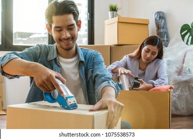 Asian Young Couple Packing Big Cardboard Box For Moving In New Place, Moving And House Hunting Concept