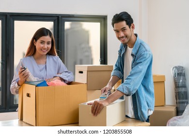 Asian Young Couple Packing Big Cardboard Box For Moving In New Home, Moving And House Hunting Concept