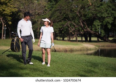 Asian Young Couple Playing Golf On Golf Course, The Male Partner Is Trainer To The Female Golfer