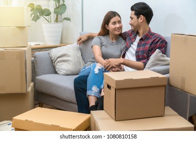 Asian Young Couple Sitting On The Sofa For Relax After Success Packing Big Cardboard Box For Moving In New Place, Moving And House Hunting Concept