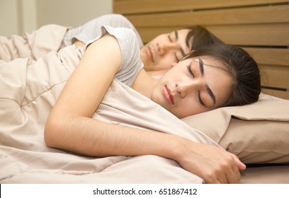 Asian Young Couple Are Sleeping On The Bed At Home.