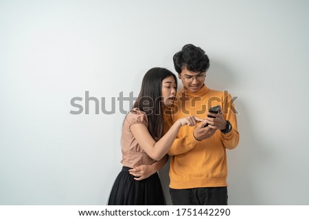 Asian young couples chatting while standing on their smart phones together with isolated backgrounds