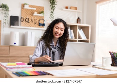 Asian young creative or graphic designer with curly hairstyle drawing or sketching on digital tablet smiling at home.Happiness female freelancer smart and confident enjoying with job or work - Powered by Shutterstock