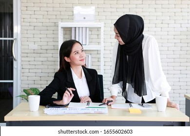 Asian Young Cute Sweet Muslim And Buddhist  Female Workers Are Discussion In Office Before After Office Hours. Bangkok Thailand South East Asia