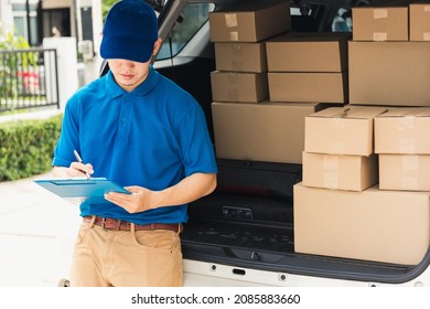 Asian young delivery man courier in uniform hold documents clipboard checking list parcel post boxes near a car for service shipment to customer, Online shopping service concepts - Powered by Shutterstock