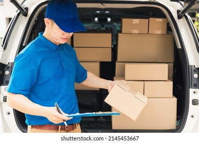 Asian young delivery man courier in uniform hold documents clipboard checking list parcel post boxes near a car for service shipment to customer, Online shopping service concepts