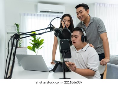 Asian Young DJ Man Speaking On Microphone At Studio With Loving Parent. Male Teenager Patient Person Feeling Happy And Relax While Recording News Podcast Show For Radio Broadcasting At Home Studio.