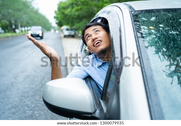asian young driver opened the window\
and watched the sky will be rain because of\
cloudy