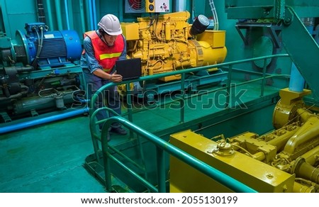 Asian young Engineer using laptop computer to checking Engine quality system inside of engine Room of nautical Ship