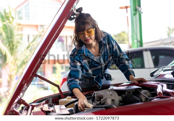 アジアの若い女性の車修理工 女性整備士は 車のエンジンのオイルレベルをチェックする 機械点検整備車のエンジンや車両を自分で持って の写真素材 今すぐ編集