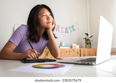 Asian young female graphic design student working project at home using tablet   laptop  Color wheel 