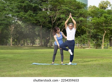 asian young female helps asian senior with grey hair doing yoga in the park, father and daughter in sportswears workout together, concept of people lifestyle, health care, family relationship - Powered by Shutterstock