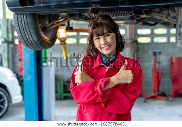 Asian Young\
Female Mechanics Smiling and Giving Thumb Up. Woman Mechanic Car\
Repair Worker in the Auto Repair. \
