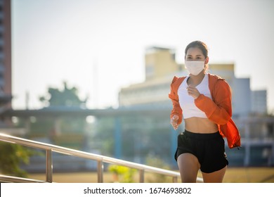 Asian Young Fitness Sport Woman Running  And She Wears A Mask For Protective Dust And Pollution And Protection Flu Virus, Influenza, Coronavirus On City 