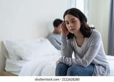 Asian young girl feel angry boyfriend having conflict domestic problem. New marriage man and woman feel heartbroken for quarrel conflict while sit on bed in bedroom. Family problem-separation concept. - Shutterstock ID 2112628280