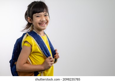  Asian Young Girl Showing Her Arm With Yellow Bandage After Got Vaccinated Or Inoculation, Child Immunization, Covid Delta Vaccine Concept