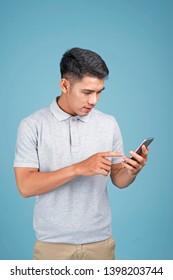 Asian Young Handsome Attractive Man With Smart Phone On Blue Background