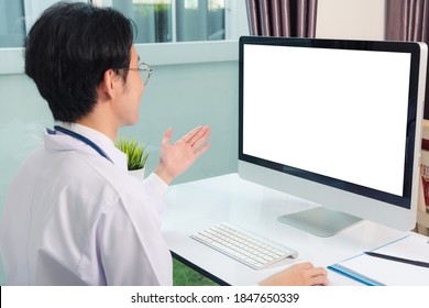 Asian Young Handsome Doctor Man Wearing A Doctor's Dress And Stethoscope Video Conference Call Or Facetime Raise Hand Say Hello To Patient He Smiling On Desk At Hospital Office, Health Medical Care