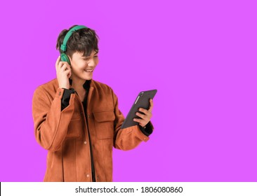 Asian young handsome man smiling and listening music by big green headphones by smartphone search. Happy boy from listen to music using technology in to smartphone isolated on purple background. - Powered by Shutterstock