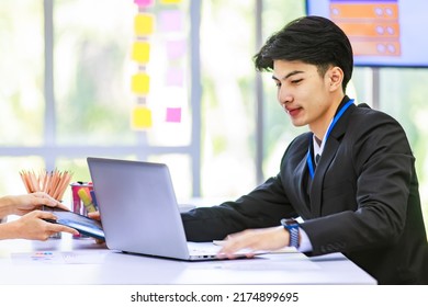 Asian young handsome professional success male businessman employee staff in formal suit sitting working with laptop notebook computer and paperwork graph chart growth target document in meeting room. - Shutterstock ID 2174899695