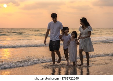 Asian Young Happy Family Enjoy Vacation On Beach In Evening. Dad, Mom And Kid Relax Walking Together Near Sea When Sunset While Travel Holiday Trip. Lifestyle Travel Holiday Vacation Summer Concept.