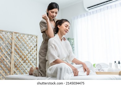 Asian Young Happy Woman Feeling Relax During Shoulder And Back Massage. Attractive Beautiful Girl Sitting On Massage Table Getting Physiotherapy Service From Masseuse For Body Care In Spa Beauty Salon