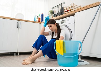Asian young housewife feeling exhausted after doing housework at home. Attractive woman housekeeper cleaner sitting on floor, feeling tired and stress to clean mess in kitchen and overworked in house. - Shutterstock ID 2075023033