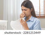 Asian young housewife woman having bad smelling clothes holding breath nose with fingers, sniff smelly dirty stinky musty, look disgusting from clothes after washed clothes, laundry out of machine.