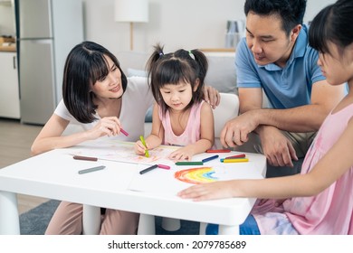 Asian Young Kid Daughter Coloring And Painting On Paper With Parents. Happy Family Activity, Little Girl Children Learn How To Draw Art Picture Enjoy Creativity With Mother And Father In Living Room.