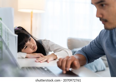 Asian young kid daughter feeling sad and need to play with busy father. Attractive parent daddy use laptop computer working from home during new normal and have no time for little child girl in house.