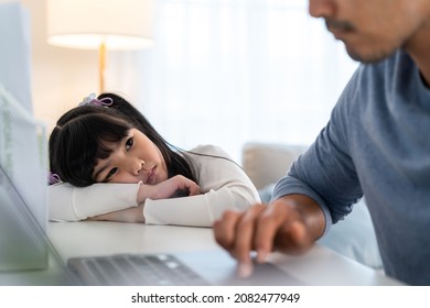 Asian Young Kid Daughter Feeling Sad And Need To Play With Busy Father. Attractive Parent Daddy Use Laptop Computer Working From Home During New Normal And Have No Time For Little Child Girl In House.