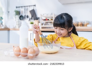 Asian Young Kid Girl Doing Pancake Homemade Bakery Alone In Kitchen. Little Cute Child Sitting On Table With Smile Feel Happy And Enjoy Learning To Cooking Foods Or Baking Kneads Yeast Dough At Home. 