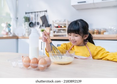 Asian Young Kid Girl Doing Pancake Homemade Bakery Alone In Kitchen. Little Cute Child Sitting On Table With Smile Feel Happy And Enjoy Learning To Cooking Foods Or Baking Kneads Yeast Dough At Home. 