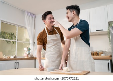 Asian Young LGBTQ Male Gay Family Enjoy Bake Bakery In Kitchen At Home. Attractive Handsome Romantic Man Couple Wear Apron Feeling Happy And Cheerful To Spending Time Cooking Foods Together In House.