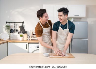 Asian Young LGBTQ Male Gay Family Enjoy Bake Bakery In Kitchen At Home. Attractive Handsome Romantic Man Couple Wear Apron Feeling Happy And Cheerful To Spending Time Cooking Foods Together In House.