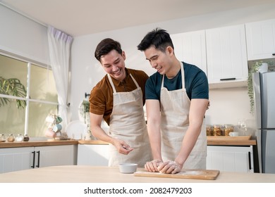 Asian Young LGBTQ Male Gay Family Enjoy Bake Bakery In Kitchen At Home. Attractive Handsome Romantic Man Couple Wear Apron Feeling Happy And Cheerful To Spending Time Cooking Foods Together In House.