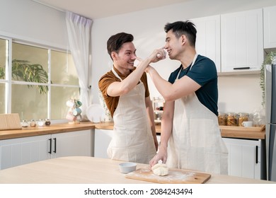 Asian Young LGBTQ Male Gay Family Enjoy Bake Bakery In Kitchen At Home. Attractive Handsome Romantic Man Couple Wear Apron Feeling Happy And Cheerful To Spending Time Cooking Foods Together In House.