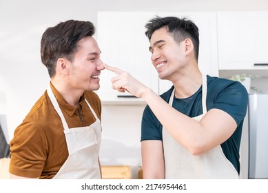 Asian Young LGBTQ Male Gay Couple Enjoy Bake Bakery In Kitchen At Home. Attractive Handsome Romantic Man Couple Wear Apron Cooking Food Feeling Happiness And Cheerful To Spend Time Together In House.