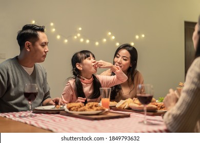 Asian Young Little Girl Enjoy Eating Her Meal Crispy Fried Chicken Together With Family In Christmas And New Year Party. The Kid Feeling Happy To Stay With Parents And Grandparents During Holiday.