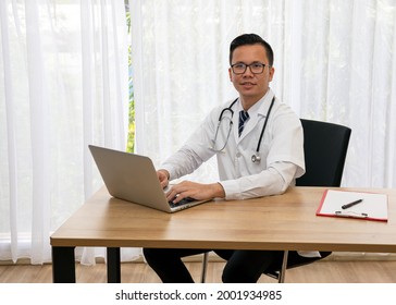 Asian Young Male Happiness Doctor Typing Laptop Sitting At Desk In Hospital Room