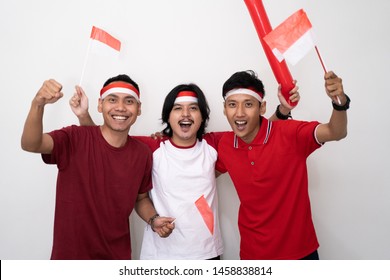 asian young male supporter of indonesia. holding flag and wearing red shirt. indonesia independence day celebration