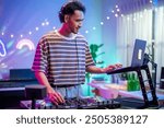 Asian young man artist DJ mixing and scratching music mixer controller. Attractive male musician DJ having fun mixing music on console touching buttons and playing electronic music at neon party.