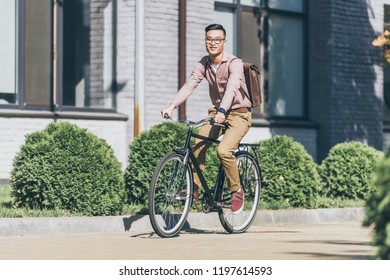  Asian Young Man With Backpack Riding Bicycle On Street