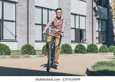  Asian Young Man With Backpack Riding Bicycle On Street