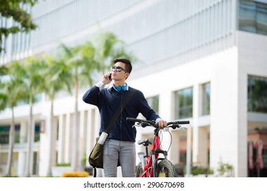 Asian Young Man With A Bicycle Talking On The Phone