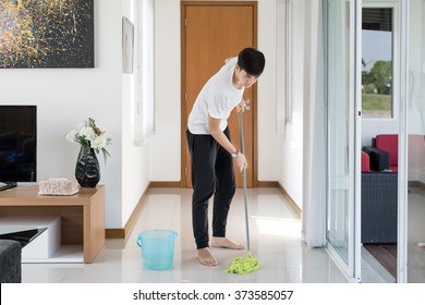 Asian Young Man Cleaning Floor At Home. 